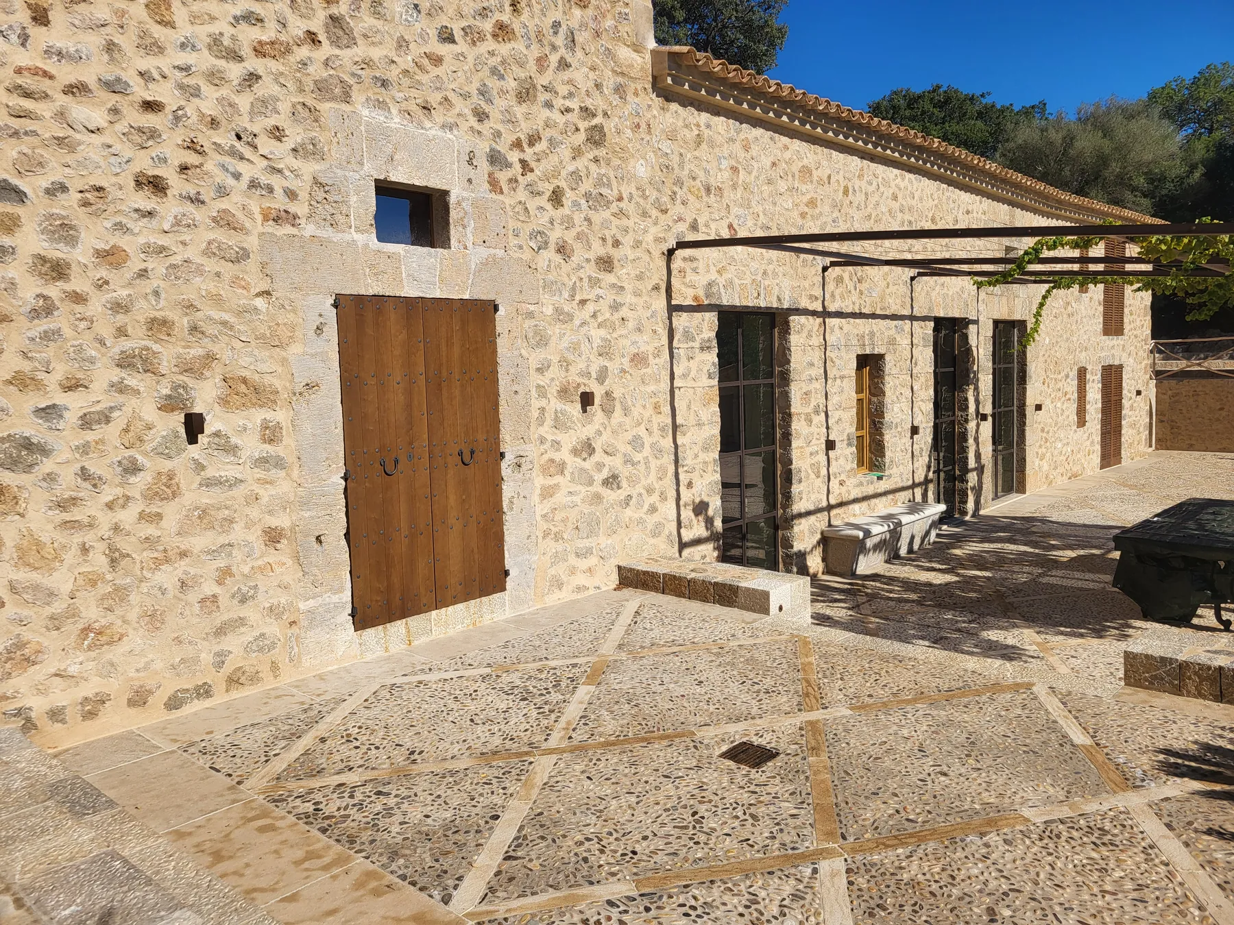 Exposed-stone facade and pergola of a renovated home in Esporles, Mallorca.